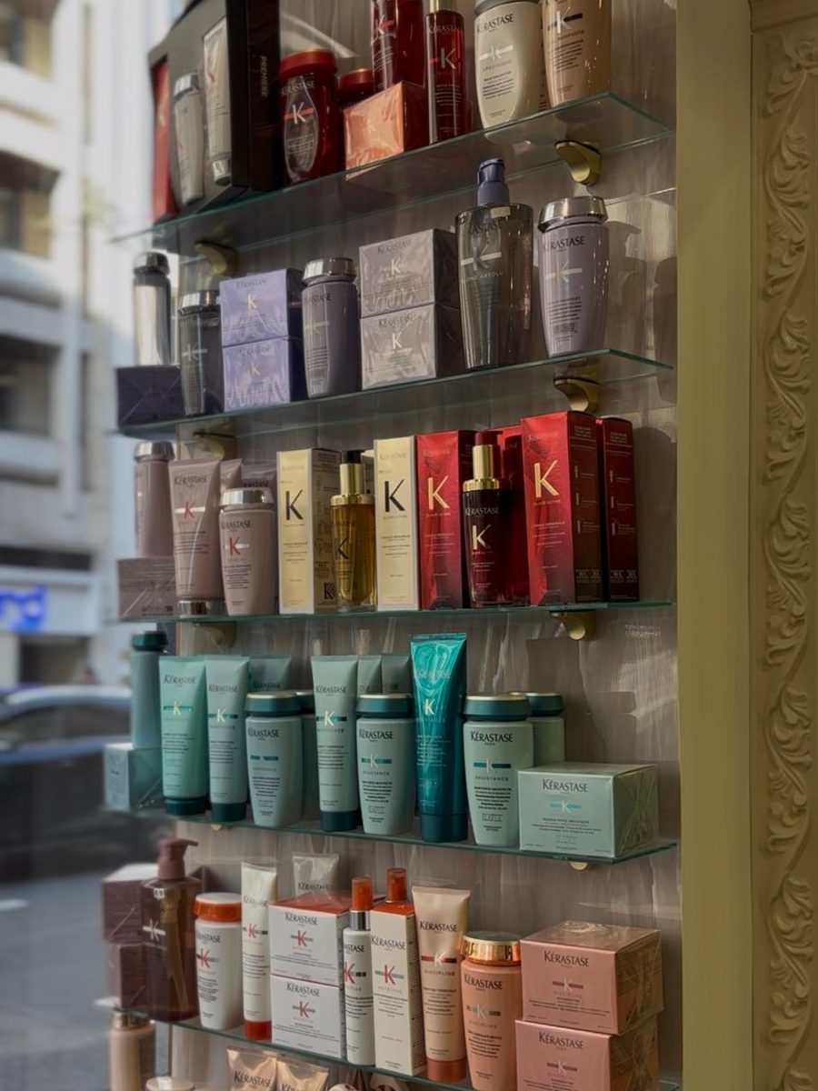 Le mur de produits Kérastase du salon Rosana, présentés sur étagères de verre.